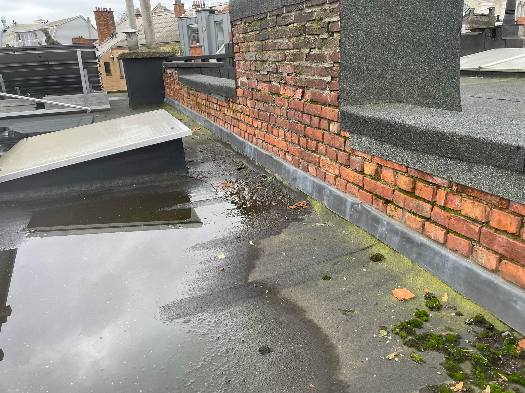 Verweerde bakstenen gevel met scheurtjes in het voegwerk en mosgroei